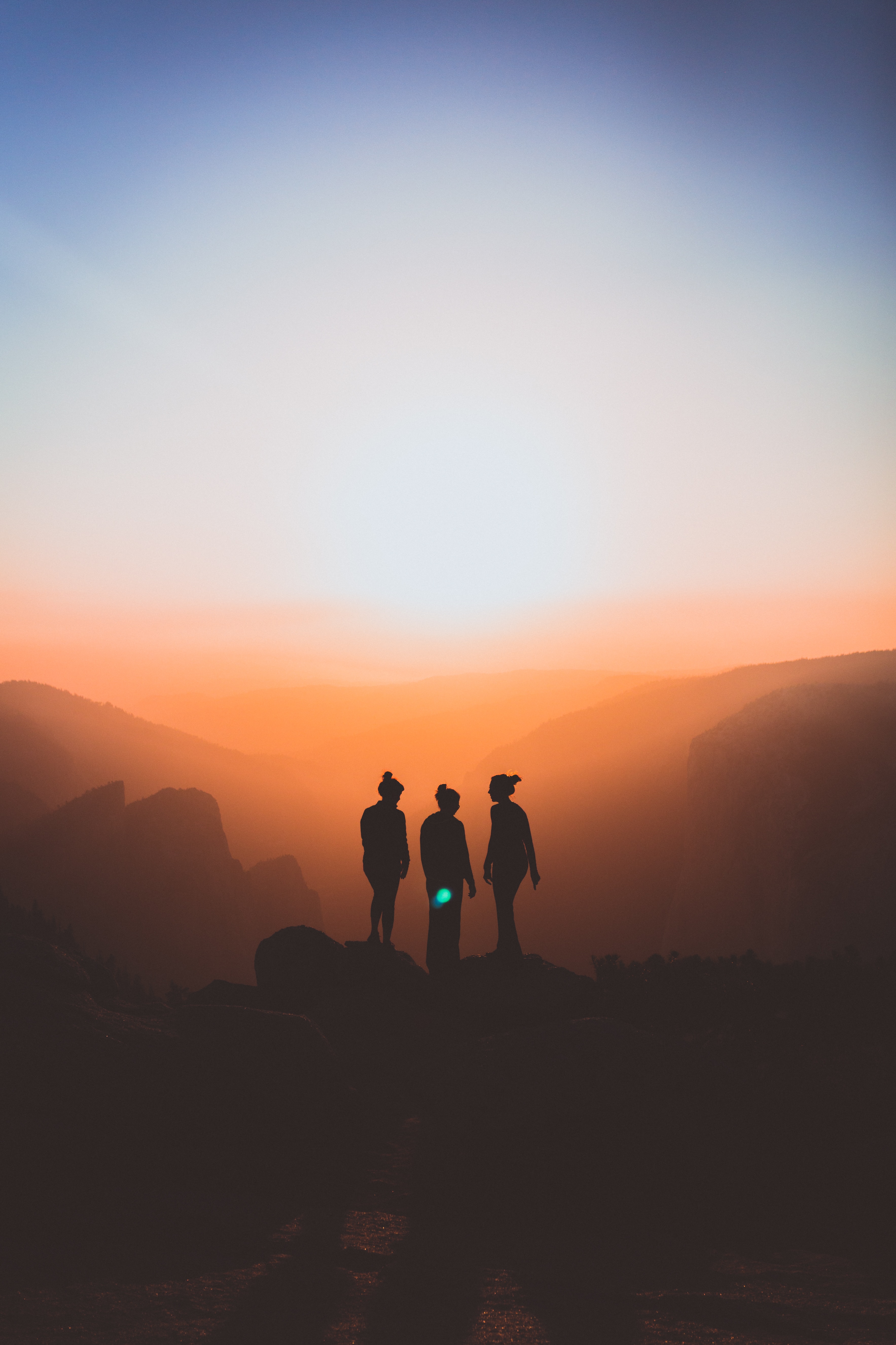 Three figures silhouetted by sunset in background, at Yosemite Park.